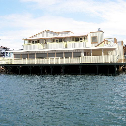 A large elevated structure with yellow trim extends over water, supported by pillars, with the sky and other buildings in the background.